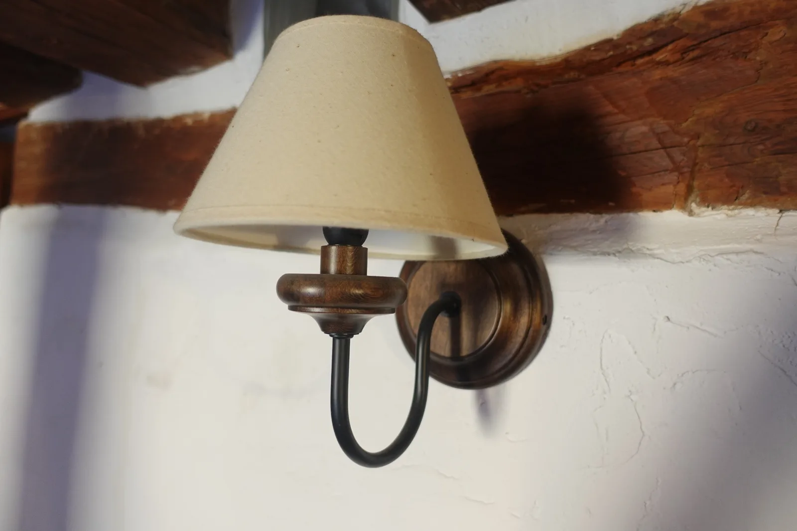 Lámpara de pared sobre vigas y muro blanco